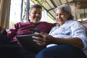 Senior biracial couple enjoys a relaxing moment with a tablet