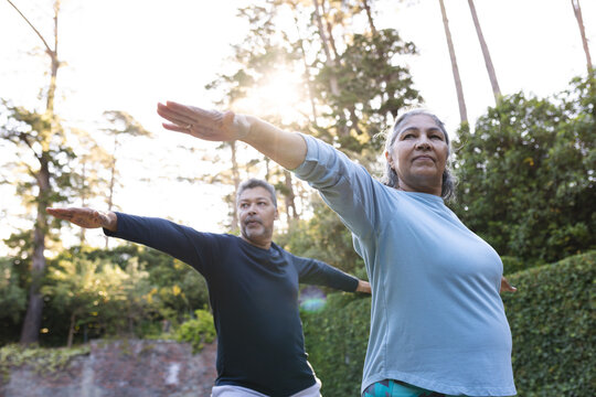 Senior biracial woman and man practice yoga outdoors at home