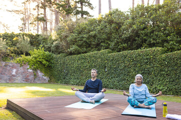 Senior biracial woman and biracial man practice yoga outdoors with copy space at home