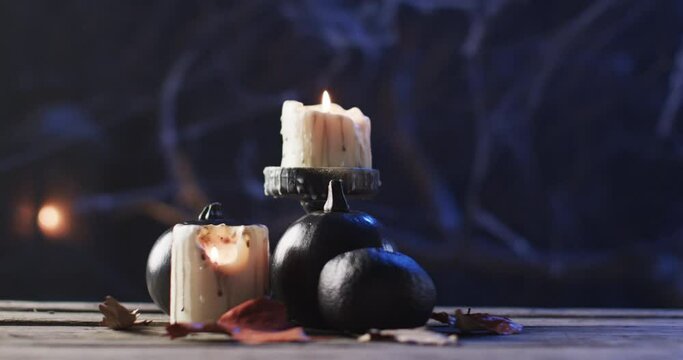 Candles and pumpkins set a spooky mood on a wooden surface