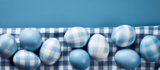 A collection of blue Easter eggs is placed neatly on top of a checkered table cloth. The eggs are vibrant in color and add a festive touch to the setting. - Powered by Adobe