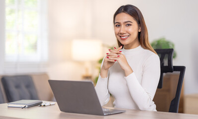 Beautiful young asian business woman working on her laptop in her home office.