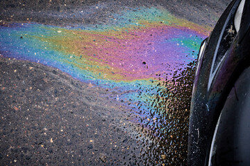 Gasoline and oil spill on wet asphalt in a parking lot near a hypermarket