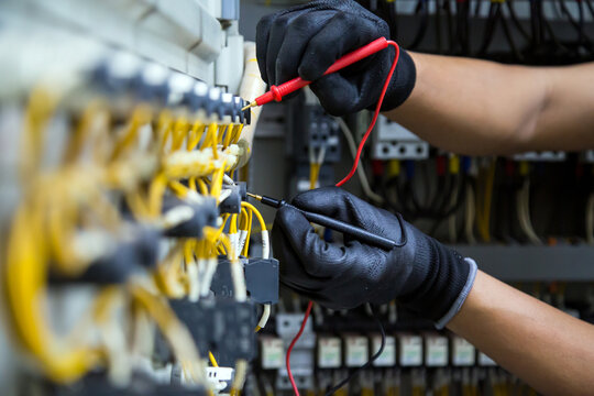 Electrician use electrical measuring tool meter at main panel circuit breaker power electricity switchboard system cabinet for repairing or safety service maintenance and electric cable wiring check.