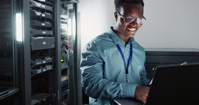 Black man, engineer and laptop in server room for database update, cyber security or coding. Computer, typing and happy technician in data center for information technology or programming software