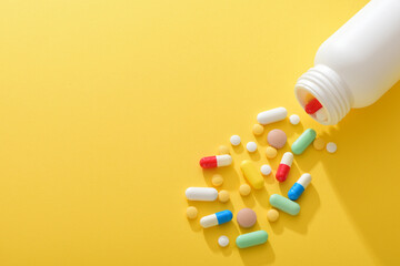 Various drugs poured out of the medicine bottle on a yellow background