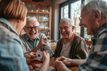 Fotobehang Group of happy senior people laughing while playing cards together at home © Kien