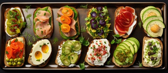 A tray overflowing with a variety of open sandwiches topped with an assortment of fresh and flavorful ingredients, meticulously arranged in a flat layout.
