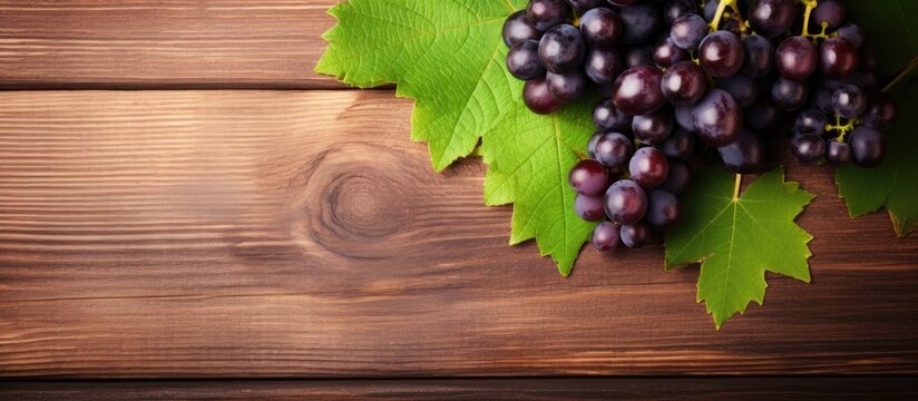A cluster of grapes, accompanied by vine leaves, is placed on top of a flat wooden table, creating a rustic and natural setting.