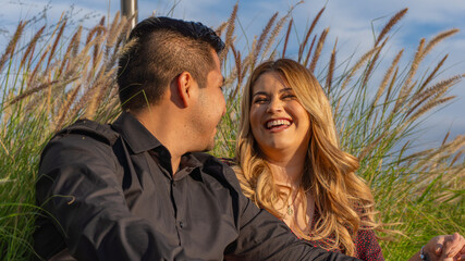 young Hispanic couple sitting on the grass laughing loudly with each other in mexico
