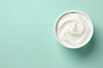 Top view of bowl with white quark or cream on side of mint green background with copy space - obrazy, fototapety, plakaty