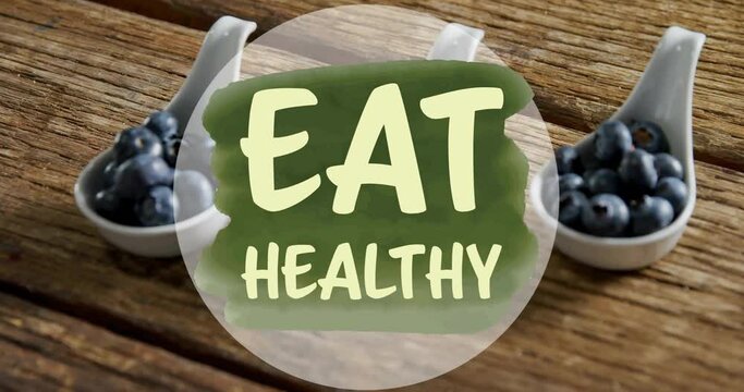 Animation of eat healthy text over blueberries on table