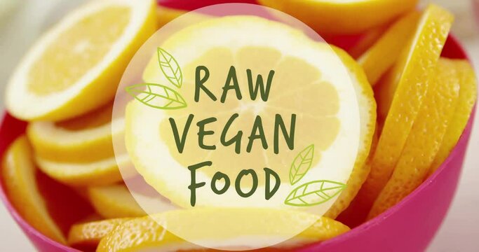 Animation of raw vegan food text over orange slices in bowl on table