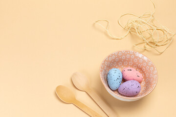 Bowl with colored Easter eggs and wooden spoons.