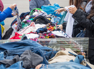 People choosing second-hand clothes at a flea market. Sustainable lifestyle, thrifting and...