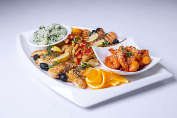 seafood mixture on a white grill. Delicious grilled fish, shrimp in sauce and salmon on the table