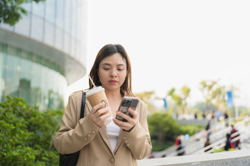 Business asian woman drinking coffee outside city building use smartphone internet connection - 749190335