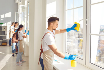 Caucasian Man from the cleaning service team wiping a window during home or office cleaning. This...