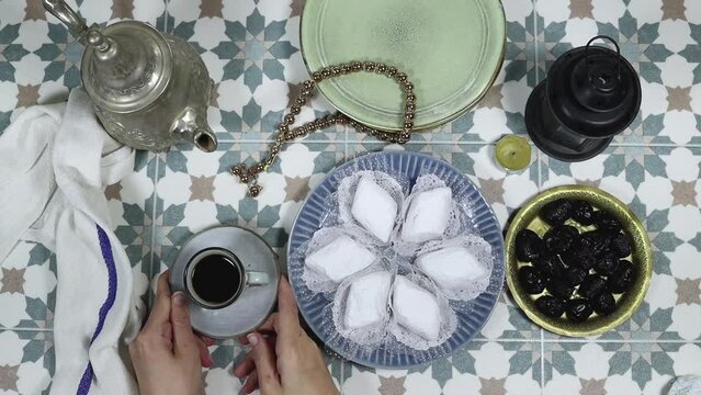 eid al fitr or aldha, ramadan concept iftar and breakfast. women drinking coffee and eating algeria cookies made from almond paste and covered with sugar powder, dates, lantern