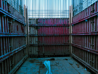 A construction site with a red wall and a blue pipe. Scene is industrial and rugged