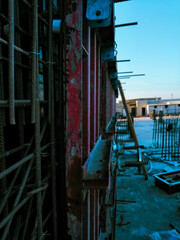 Fototapeta na wymiar A construction site with a red wall and a blue pipe. Scene is industrial and rugged
