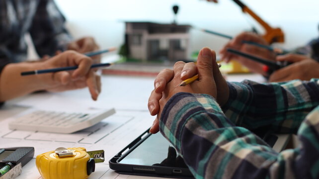 Closeup of hands engineer and architect team discussed about construction and architectural drawings works.