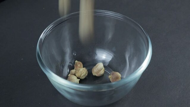 cardamom sprinkled into a glass bowl on a black table