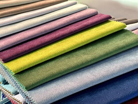 Samples of fabrics for upholstery, roman blinds. Multicolored fabric swatches spread out in a circle.