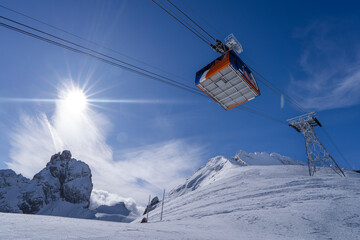 Fototapeta na wymiar Sun-Kissed Peaks and Vibrant Cable Car in the Italian Alps