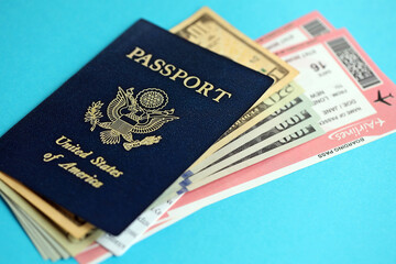 Blue United States of America passport with money and airline tickets on blue background close up. Tourism and travel concept