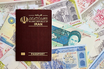 Red Islamic Republic of Iran passport and iranian reals money bills background close up. Tourism and travel concept