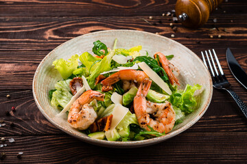 Snack salad of shrimp, avocado, sun-dried tomatoes, parmesan cheese, lettuce and arugula.