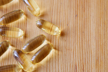 Omega-3 capsules on a wooden surface, top view, close-up