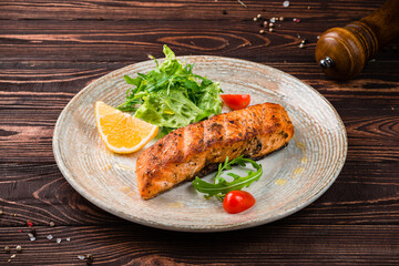 Grilled salmon fillet with cherry tomatoes, lemon and greens.