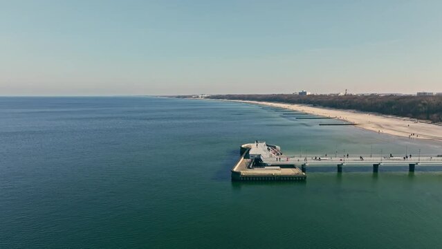 Sunny winter day at Kołobrzeg pier. Quiet sea, no waves. People enjoying a stroll.