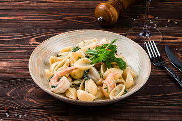 Lunch pasta with shrimp, cream sauce and arugula in plate.