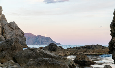 Sudak, Crimea. Moon rise. Cape Rybachy. Mount Meganom in the light of the setting sun