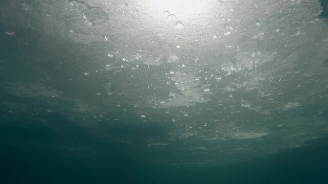 Underwater view on sunlight penetrating under ice, Slow motion. Sun through thin ice, moving forward below ice, ice diving, underwater ice texture, natural background
