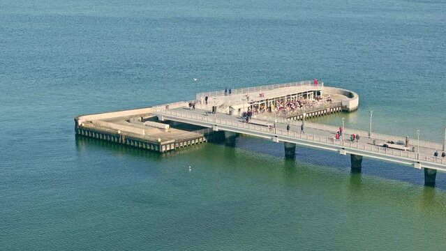 Winter afternoon at Kołobrzeg pier. Calm sea, cloudless sky. Tourists walk along the pier.