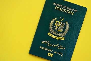 Green Islamic Republic of Pakistan passport on yellow background close up. Tourism and citizenship...