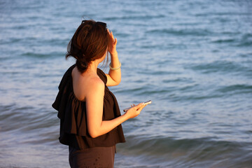 Girl standing with smartphone in hand on sea beach