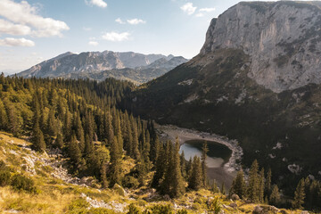 Small lake in the shadow of the mountain's peak surrounded by forest, Durmitor, Montenegro