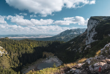 Small lake in the shadow of the mountain's peak surrounded by forest, Durmitor, Montenegro