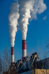 Industrial landscape with smokestack in winter and blue sky