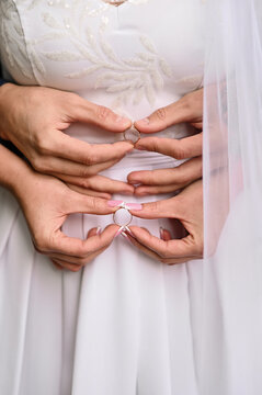 wedding rings in the hands of the bride and groom. vertically