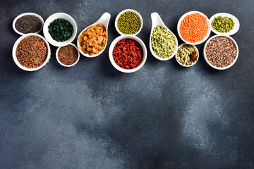Banner with various superfoods in bowls on black stone background. Top view. Free space for text.