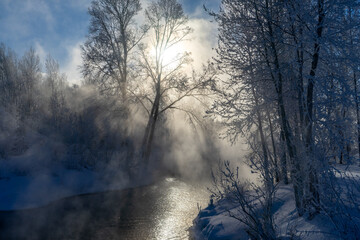 Winter landscape with fog on the river and trees in hoarfrost