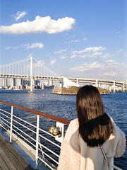 レインボーブリッジを船から眺める女性の後ろ姿
