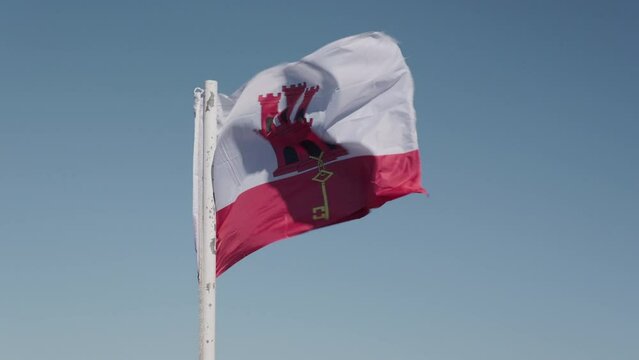 Slow motion of the Gibraltar flag waving with sky in background