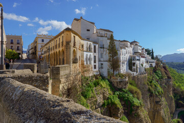 Fototapeta na wymiar view of the buildings of the city of ronda,malaga,spain at the edge of the cliff with a blue sky with clouds